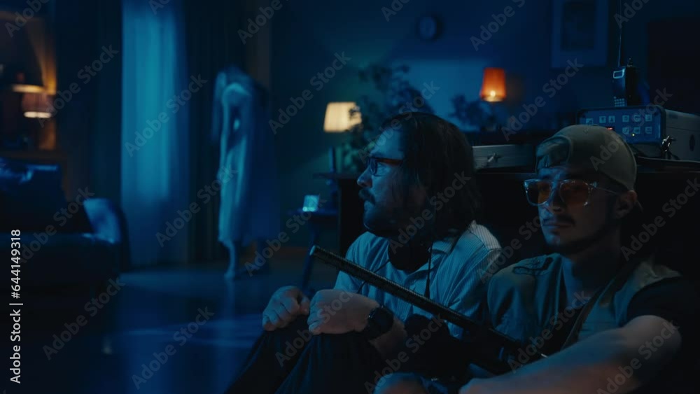 Two ghost hunters hiding behind the table. A female silhouette , ghost, entity standing on the background, then running towards them. The men are scared and frightened. Two ghost hunters hiding behind the table. A female silhouette , ghost, entity standing on the background, then running towards them. The men are scared and frightened.