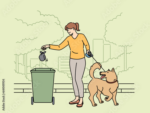 Woman walking dog throws bag of puppy poop into trash can, taking care of cleanliness of park. Smiling girl cleaning up after dog on street, showing responsibility and love for environment