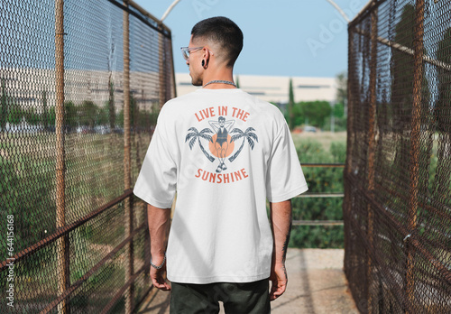 Mockup of man wearing t-shirt with customizable color in urban setting, rear view