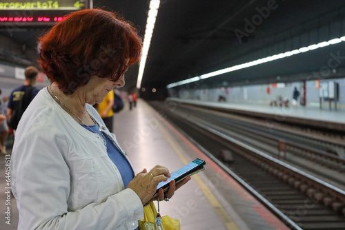 Obraz na plátně woman waiting for the train with the phone