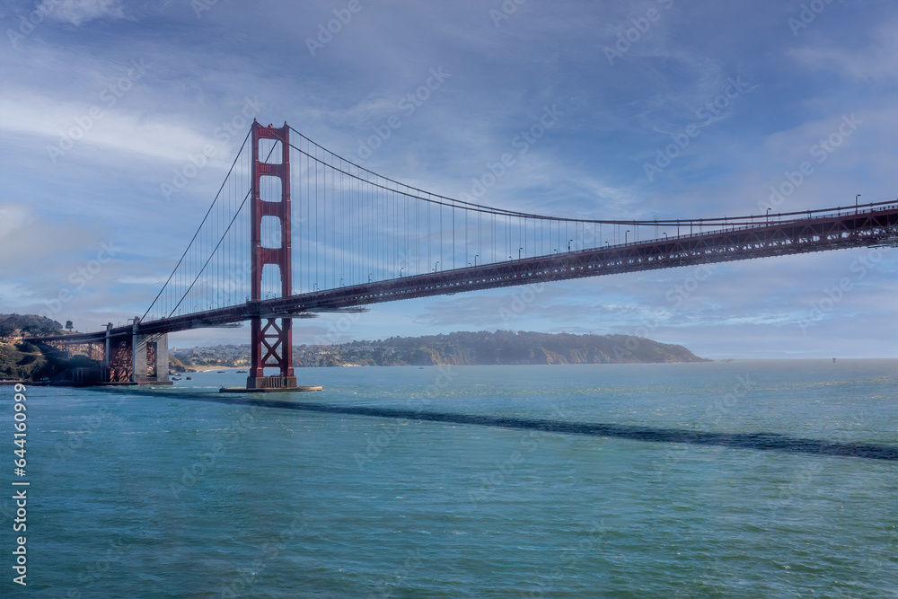 San Francisco, CA, USA - July 13, 2023: Golden Gate bridge south landing with 1 tower under blue cloudscape and green ocean water.