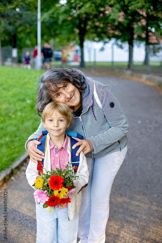 First day at school for a firstgraden, child starting school, bringing flowers for the teacher, family going with him