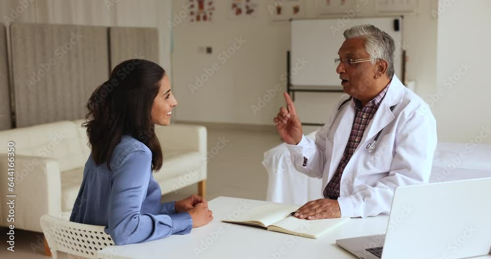 Indian man GP provide medical assistant to young female patient, finish visit in clinic shake hands express respect for getting professional advice, feel satisfied with health checkup and consultation Indian man GP provide medical assistant to young female patient, finish visit in clinic shake hands express respect for getting professional advice, feel satisfied with health checkup and consultation