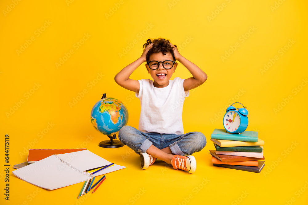 Full length photo of excited funky little boy dressed white t-shirt studying hands arms head isolated yellow color background Full length photo of excited funky little boy dressed white t-shirt studying hands arms head isolated yellow color background