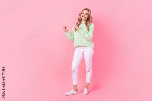 Full size photo of lovely positive girl indicate fingers empty space proposition isolated on pink color background