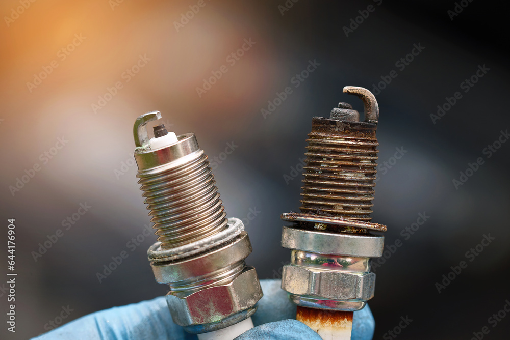 Spark plugs compare, new and old copper spark plugs. Spark plugs with worn electrodes and new one. Selective focus. Electrical ignition parts of gasoline engine.
