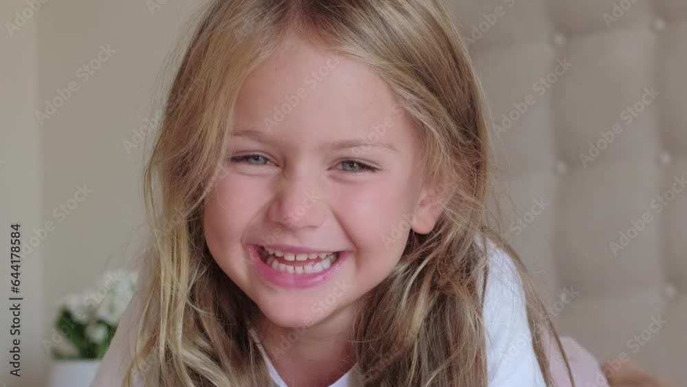 toddler little girl smiling teeth at home on bed in morning looking at camera, cute kid child with pretty face. Children happy day positive emotions. Slow motion closeup
