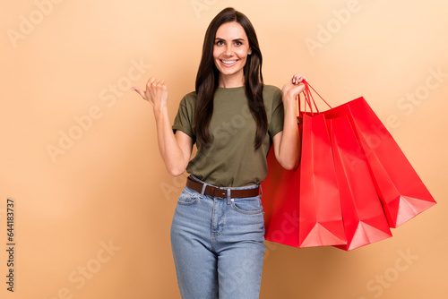Photo of excited pretty lady wear khaki t-shirt rising bargains thumb empty space isolated beige color background
