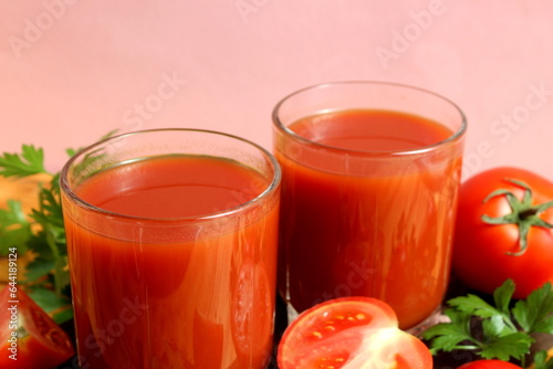 Two glasses of tomato juice stand on a wooden table.