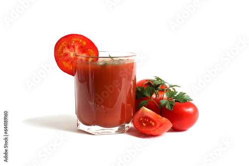  On a white background is a glass of tomato juice with tomatoes and herbs.