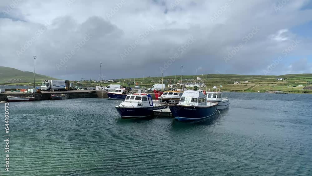 Fishing and tourists boats docked at Portmagee port, harbour. Water is waving from a heavy wind. Famous town, village on Ring of Kerry. Valentia island in the background. Portmagee, Kerry, Ireland Fishing and tourists boats docked at Portmagee port, harbour. Water is waving from a heavy wind. Famous town, village on Ring of Kerry. Valentia island in the background. Portmagee, Kerry, Ireland