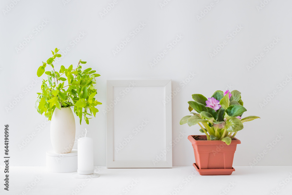 Fototapeta premium Mockup with a white frame, flowers in a pot on a light background. Empty poster frame mockup for presentation design, text, lettering