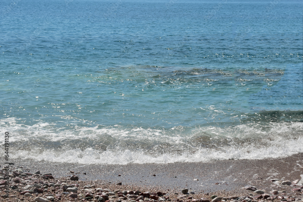 Waves on the beach. Blue water, sand and small rocks. Waves on the beach. Blue water, sand and small rocks.