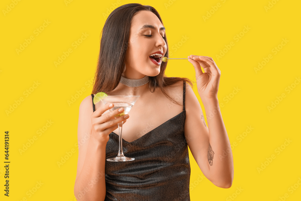 Beautiful woman with martini eating olives on yellow background Beautiful woman with martini eating olives on yellow background