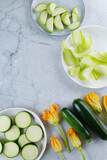 Pieces of sliced zucchini squash on white plate on marbel background. Flat lay, top view. Vegetarism concept. vertical.
