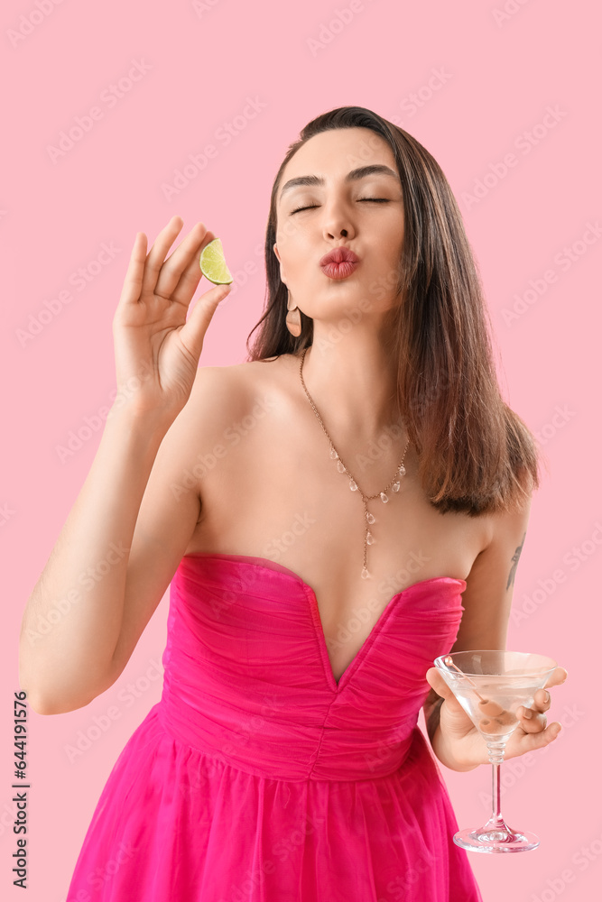 Beautiful woman with martini and lime blowing kiss on pink background Beautiful woman with martini and lime blowing kiss on pink background