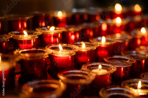 Several rows of burning votive candles in a dark European Catholic church in Rome Italy seeking favor from the Lord or saint
