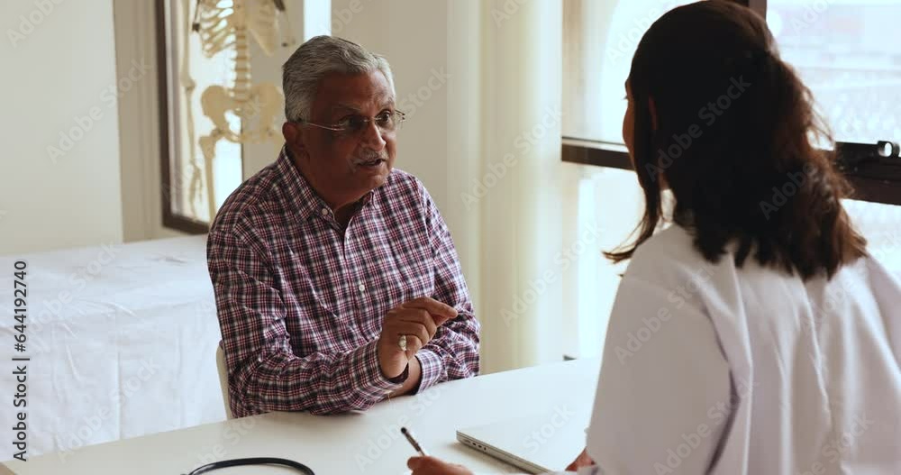 Old Indian retired man talk to woman physician in clinic office, asks about treatment, receive professional consultation meet in hospital with qualified licensed cardiologist. Gerontology, healthcare Old Indian retired man talk to woman physician in clinic office, asks about treatment, receive professional consultation meet in hospital with qualified licensed cardiologist. Gerontology, healthcare