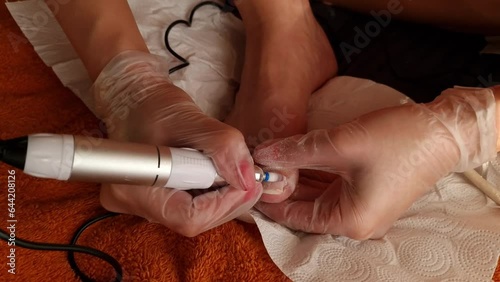 Woman removes nail polish using the electric milling machine during pedicure. Cosmetology, body care concepts