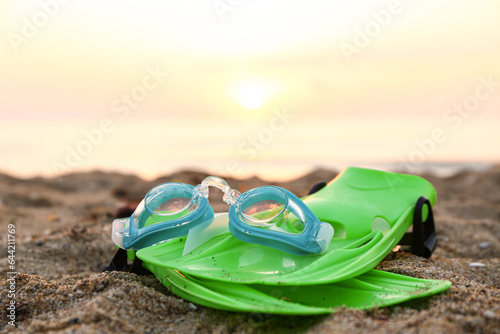New swimming mask and flippers on sand near sea © Pixel-Shot