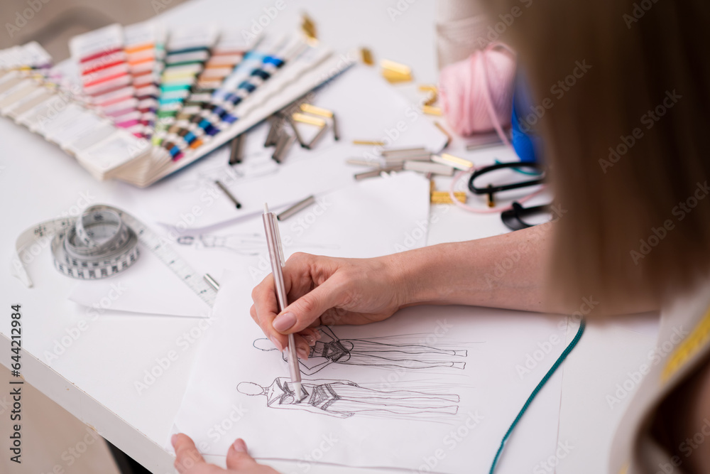 Designer draws future women dress sketch with pencil on paper working in fashion atelier skilled dressmaker creates new garment models at workplace in shop closeup Designer draws future women dress sketch with pencil on paper working in fashion atelier skilled dressmaker creates new garment models at workplace in shop closeup