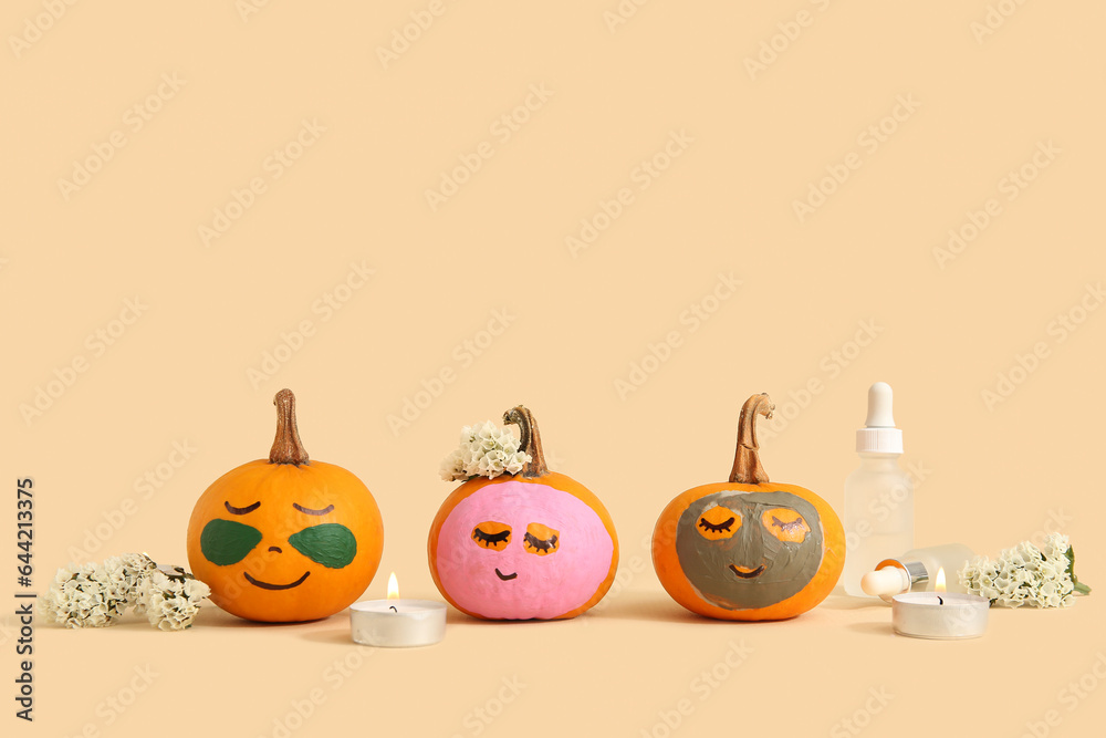 Pumpkins with masks, flowers, candles and cosmetic dropper bottles on beige background Pumpkins with masks, flowers, candles and cosmetic dropper bottles on beige background