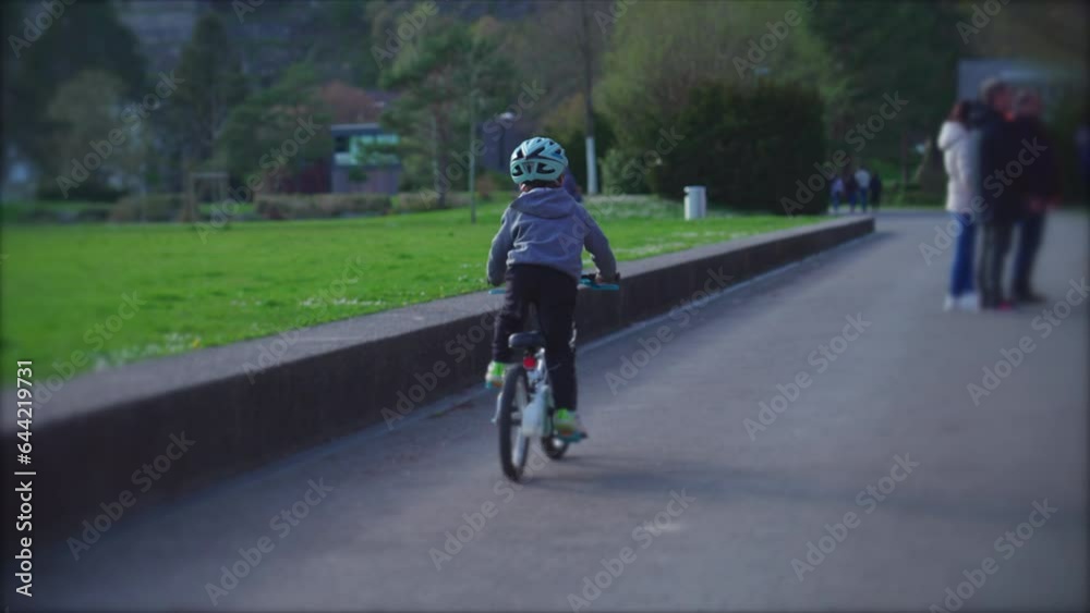Energetic little boy riding bicycle outdoors at park, child wearing protective helmet rides bike Energetic little boy riding bicycle outdoors at park, child wearing protective helmet rides bike