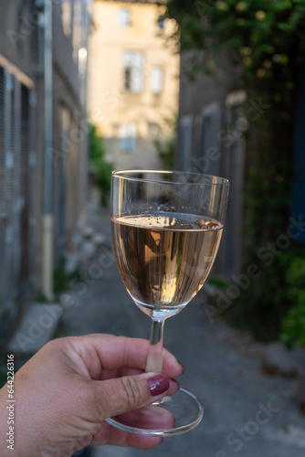 French rose dry wine from Provence in glass in sunny day with view on old streets of Arles town in sunny day