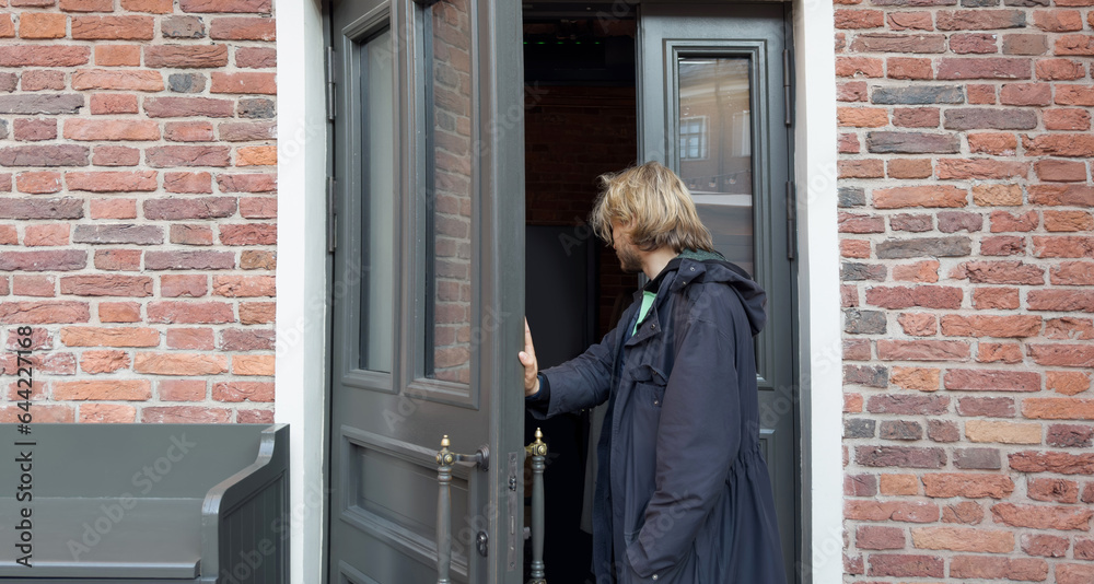 young man opening the front door, warm sunny day young man opening the front door, warm sunny day