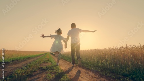 Children in together run through wheat field at sunset. Kids boy girl play fun run holding hands. Happy family. Carefree child in summer. Childhood dream concept. People, nature vacation. Farmer child