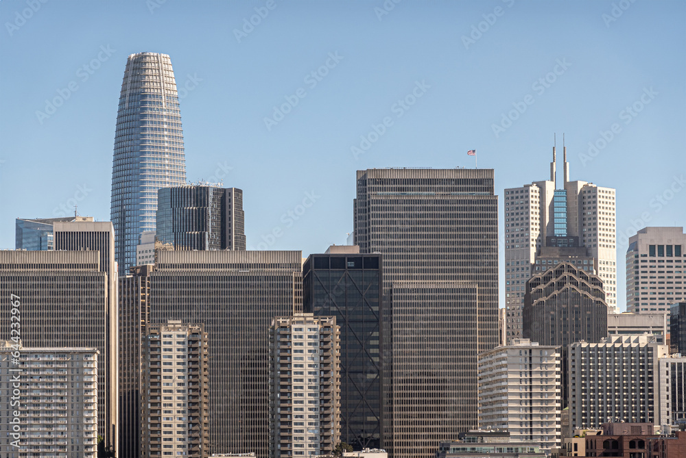 San Francisco, CA, USA - July 13, 2023: Urban jungle of tall skyscrapers with Salesforce building peeking over the rest and California Center with its 2 sharp spires to the right, Light blue sky San Francisco, CA, USA - July 13, 2023: Urban jungle of tall skyscrapers with Salesforce building peeking over the rest and California Center with its 2 sharp spires to the right, Light blue sky