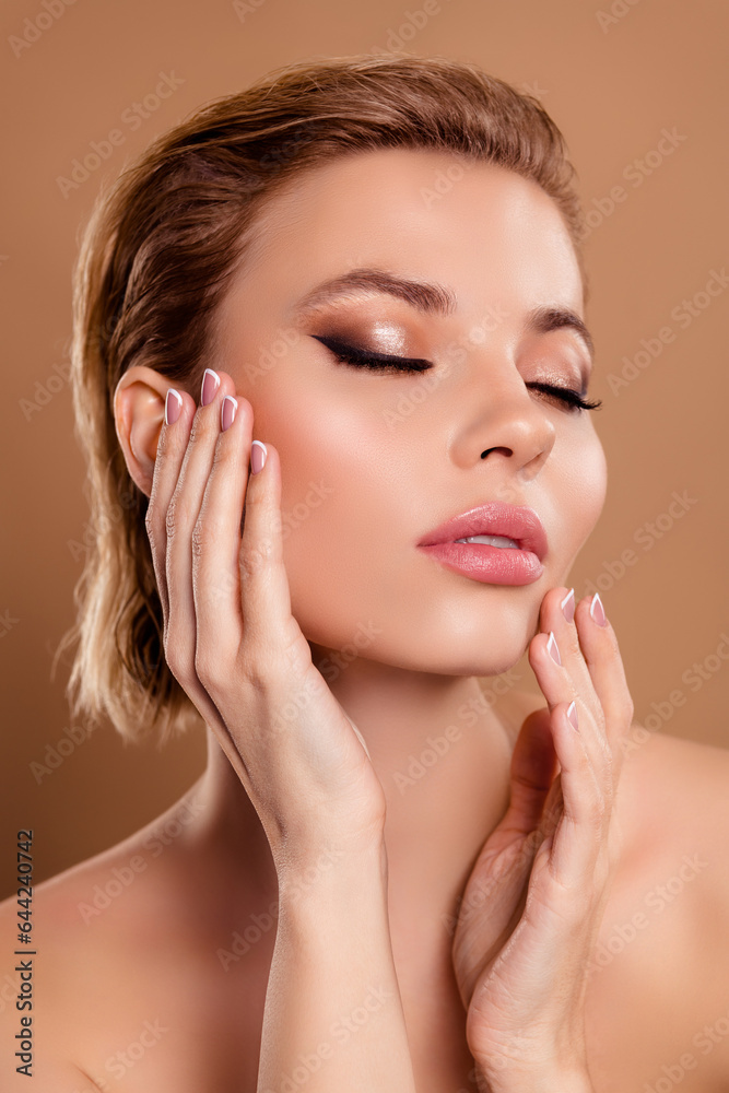 Vertical photo of smiling dreamy lady nude shoulders arms touching cheeks closed eyes isolated brown color background
