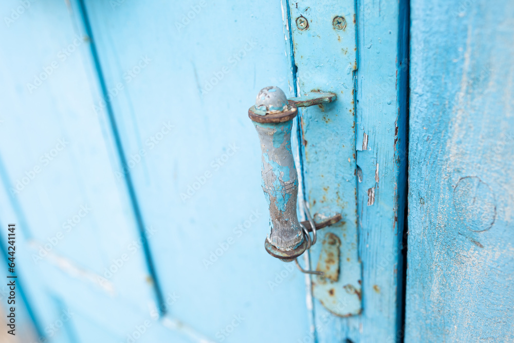 vintage old blue color door handle. peeling paint on wood doors