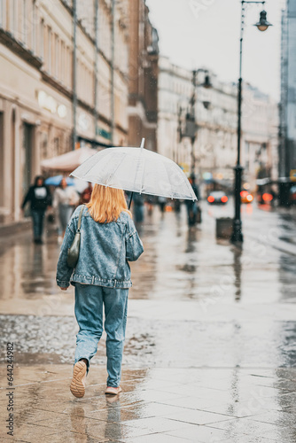 Abstract silhouette of girl walking on rain under umbrella  street scene  back view. Seasons  weather  city lifestyle