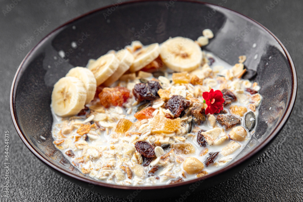 fresh granola bowl milk, dried fruit and banana tasty breakfast meal food snack on the table copy space food background rustic top view 