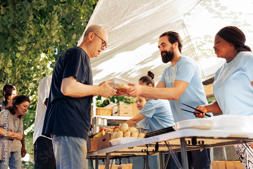 Фотография Multicultural team of humanitarian aid workers at food drive, sorting through donated food to ensure efficient distribution to less fortunate