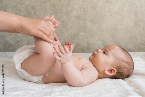 Skilled hands of masseur on newborn's legs. Concept of beneficial infant therapies