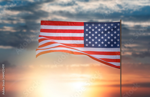 Flag of the United States. American flag against the backdrop of sunset or sunrise.