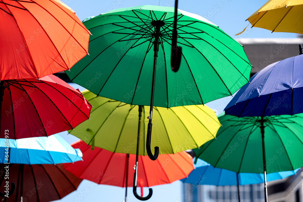 many colorful umbrellas fly and hover on the city street