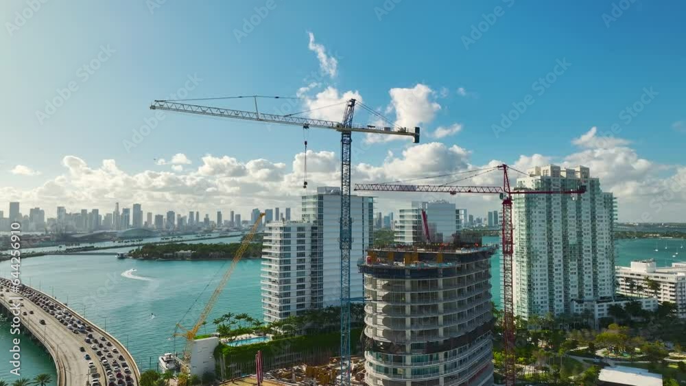 Tower lifting cranes at high residential apartment building construction site. Real estate development in Miami urban area