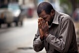 Emotive image of a standing male aged 30 praying in the street