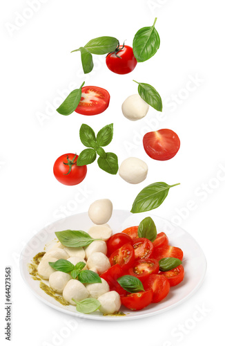 Fresh tomatoes. mozzarella cheese and basil leaves falling onto plate with Caprese salad against white background