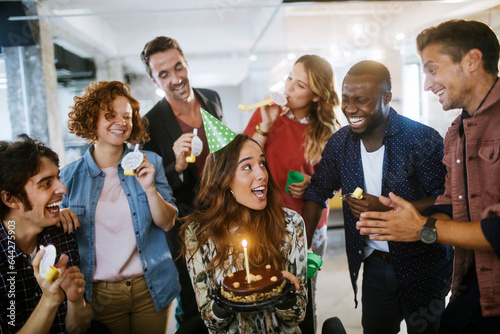 Young and diverse group of people celebrating a surprise birthday party in the office of a startup company