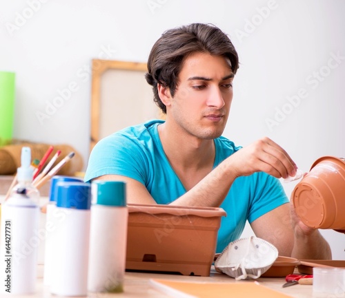 Young man decorating pottery in class