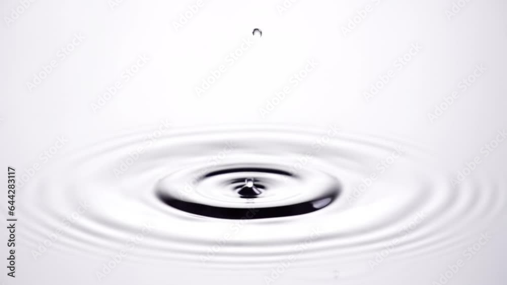 A single drop of water falling into a pool of water in slow motion ...