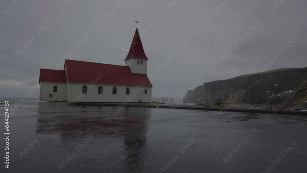 Approaching to Vík i Myrdal Church on Hill Above Sea and Coastline of Iceland on Dark Cloudy Rainy Day Approaching to Vík i Myrdal Church on Hill Above Sea and Coastline of Iceland on Dark Cloudy Rainy Day