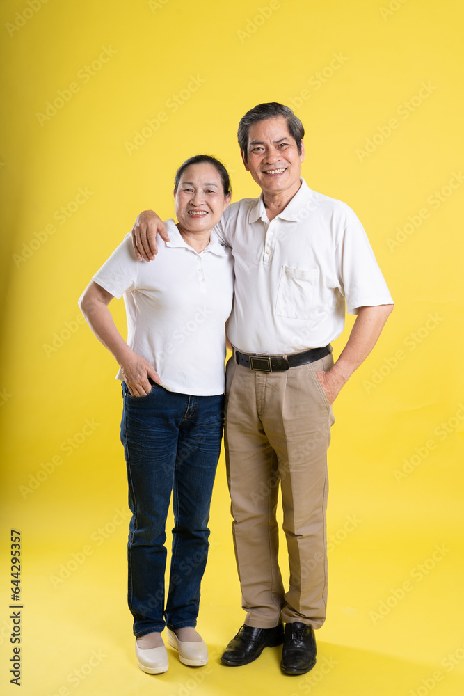 portrait of middle aged asian couple posing on yellow background portrait of middle aged asian couple posing on yellow background