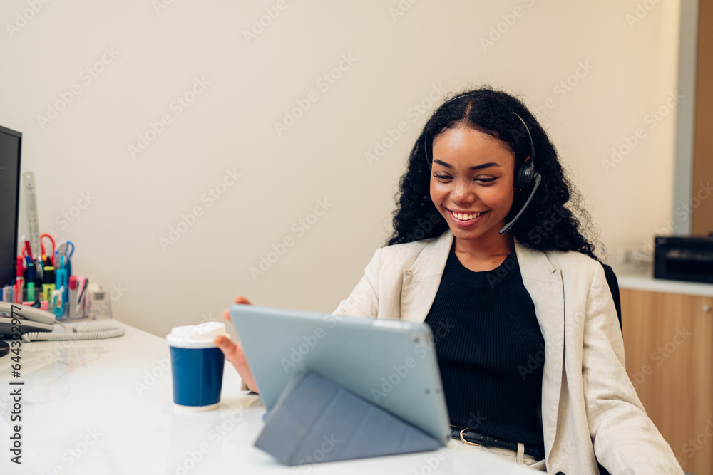 Friendly smiling woman call center operator with headset using computer, Customer service, Call center worker accompanied by her team at office Friendly smiling woman call center operator with headset using computer, Customer service, Call center worker accompanied by her team at office