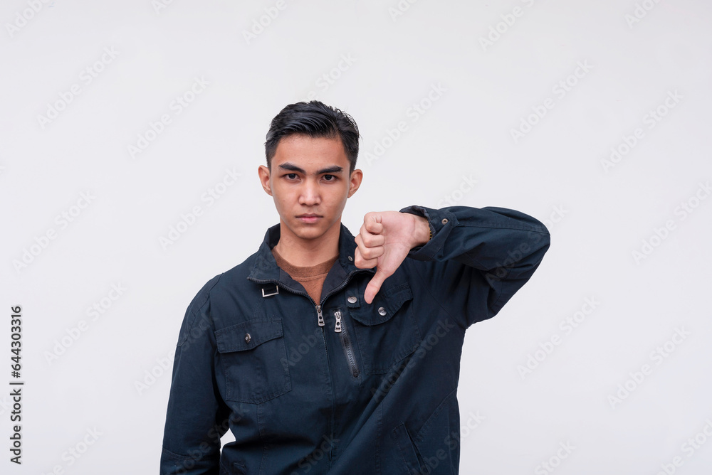 A unsympathetic young Filipino man turning down an offer, giving the thumbs down. Isolated on a white background. A unsympathetic young Filipino man turning down an offer, giving the thumbs down. Isolated on a white background.