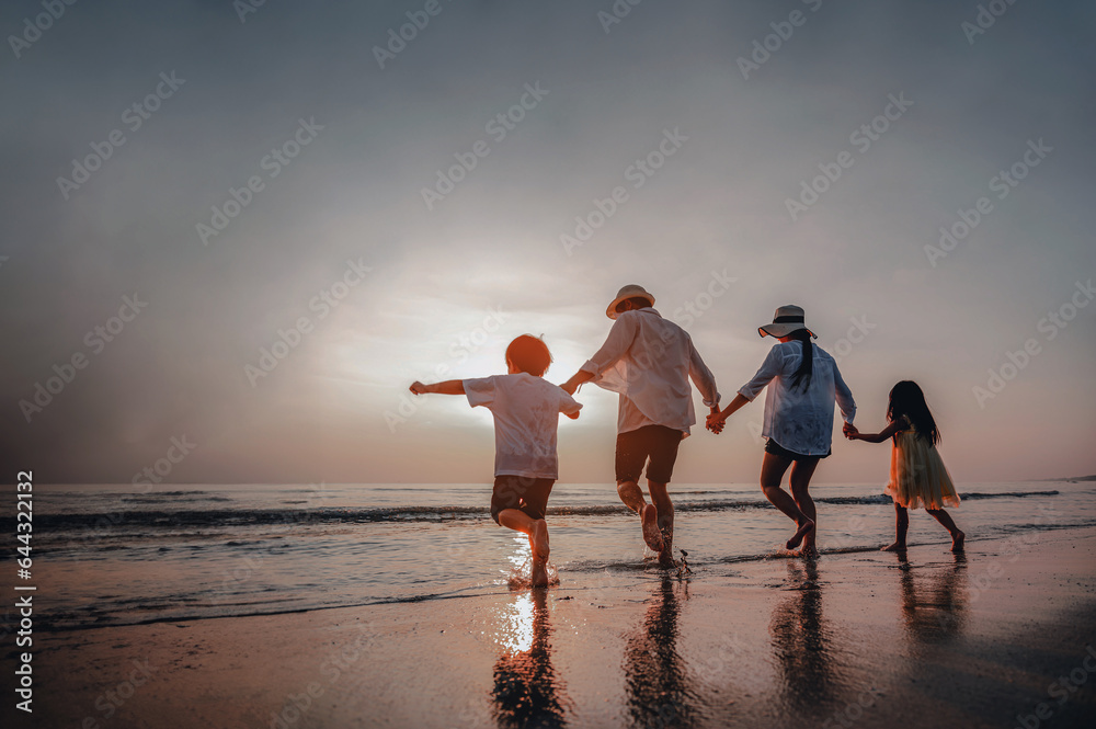 Fototapeta premium Happy Asian family consisting of father, mother, Son and daughter having fun playing on the beach.